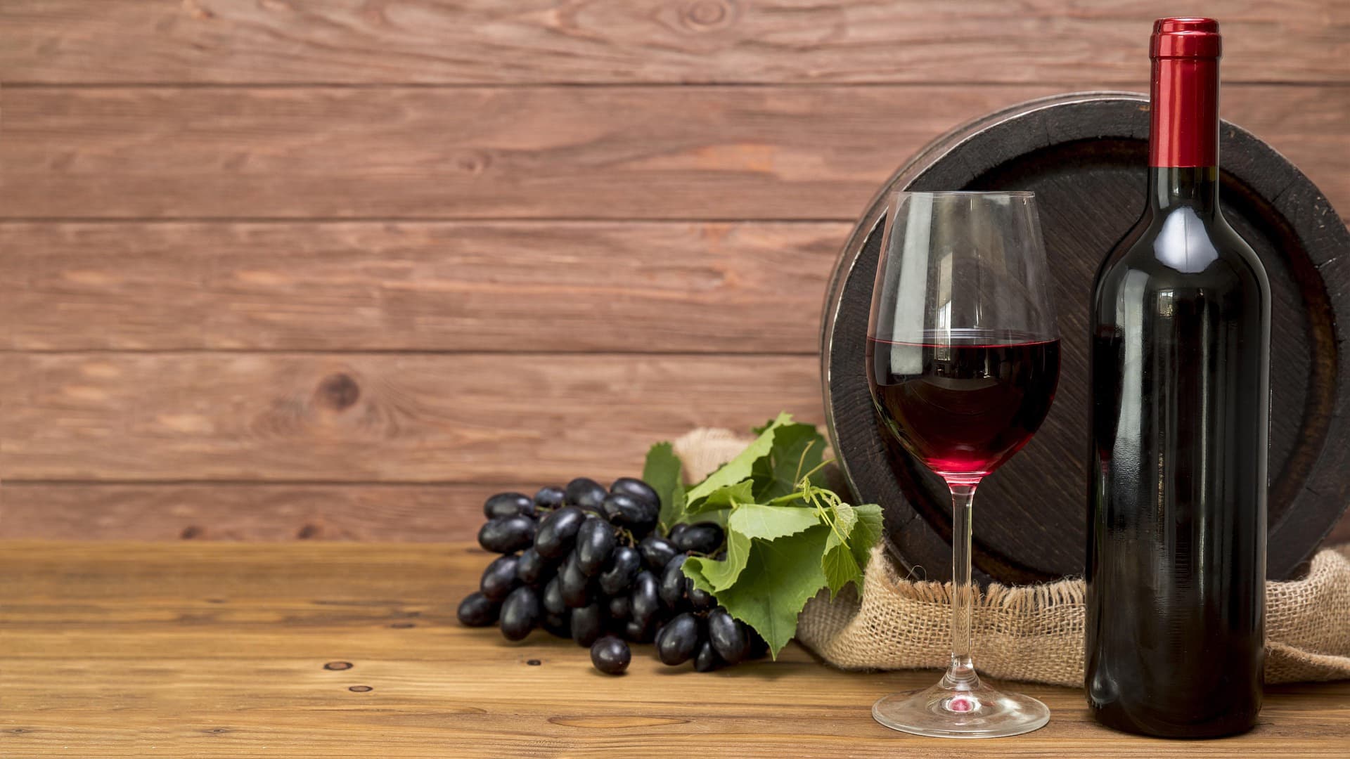 bottle of wine glass of wine and grapes on a table